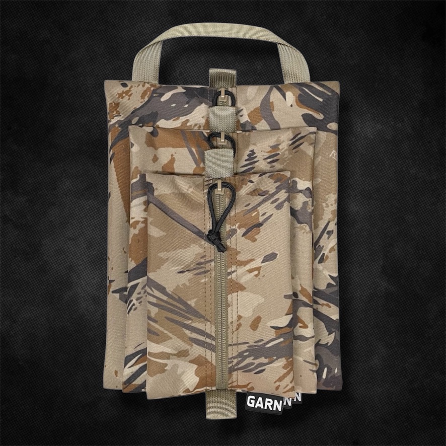Three nested arid-camo zip pouches with webbing pull tabs and a GARN label on a black textured ground